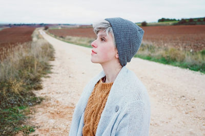 Close-up of woman wearing knit hat while standing on dirt road