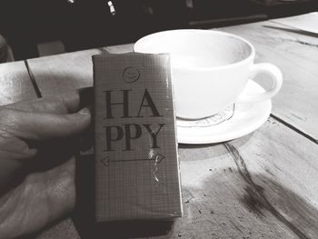 Close-up of hand holding coffee cup on table