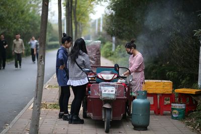 Rear view of people standing on road in city