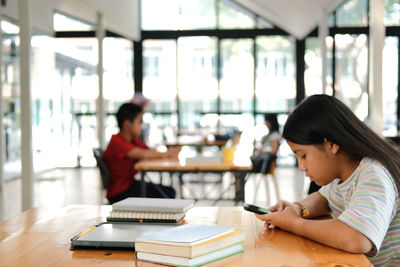 Rear view of woman sitting on table