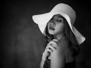 Woman wearing hat standing against black background