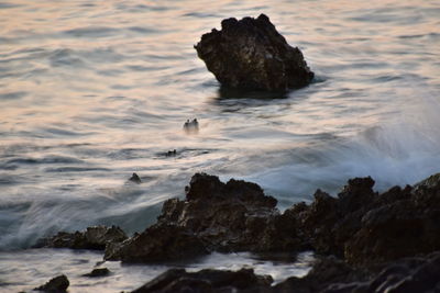 Rocks on beach against sky during sunset