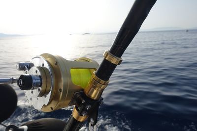 Close-up of fishing rod in sea against sky