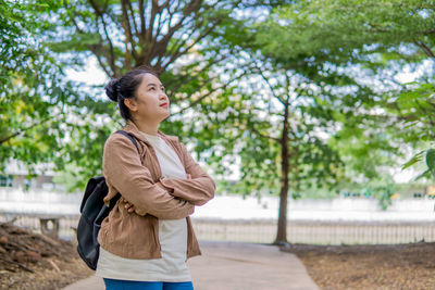 Portrait of young man standing against trees