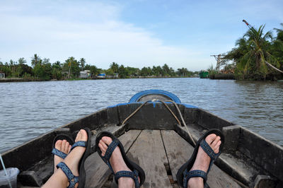 Low section of man and woman on boat sailing in river