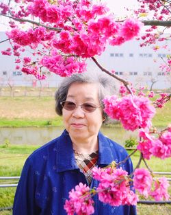 Portrait of woman standing by pink flowering plant