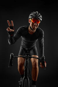 Portrait of young man riding bicycle against black background