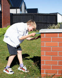 Side view of young man standing against wall