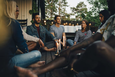 Male and female friends sitting with eyes closed in balcony during group session