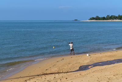 Rear view of man on beach against sky