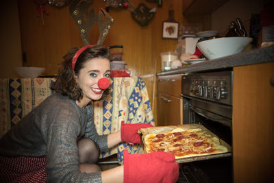 Portrait of smiling woman baking food in oven