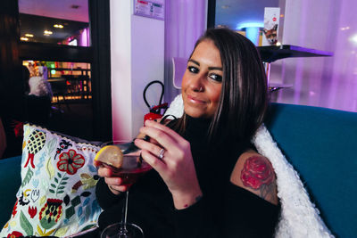 Close-up portrait of young woman having drink at bar