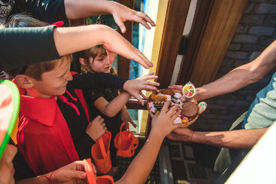 Midsection of woman giving candies to kids