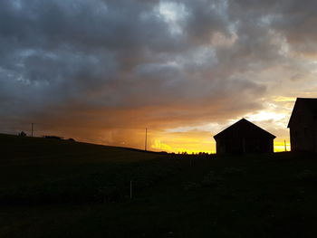 Scenic view of landscape against cloudy sky at sunset