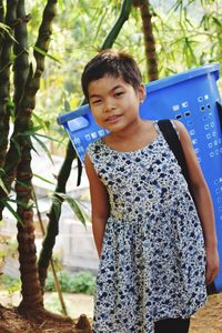 Portrait of smiling girl carrying basket on back against trees