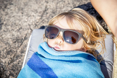 Child in sunglasses wrapped in beach towel