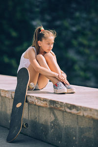 Girl looking away while sitting on wood