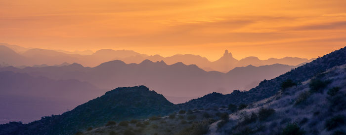 Scenic view of mountains against cloudy sky during sunset