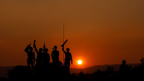 Silhouette group of special forces sodiers hold the guns on tank to indicative of their victory 