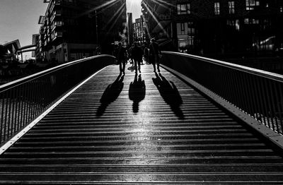 Rear view of people walking on footbridge in city