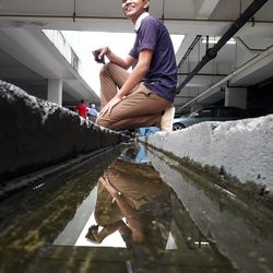 Side view of young man crouching over water