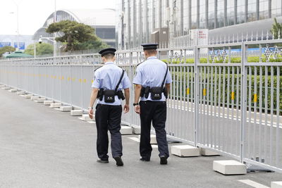 Rear view of police men walking on sidewalk