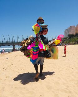 Woman with umbrella on beach against clear sky