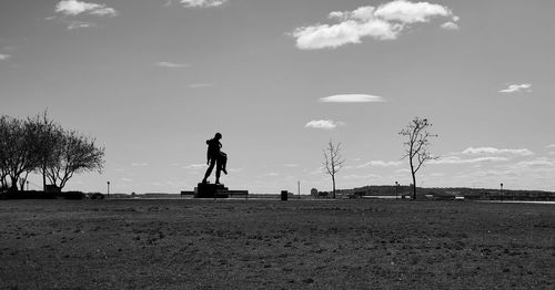 Silhouette statue on field against sky