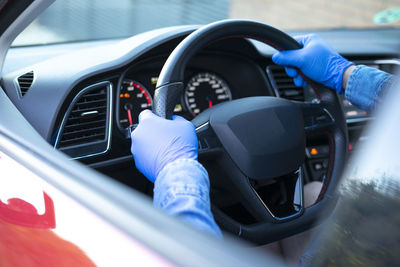 Close up of man with gloves taking the wheel of the car. covid-19.