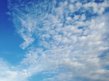 Low angle view of power lines against blue sky