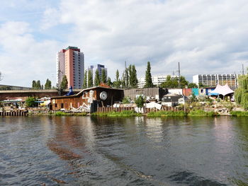 Bridge over river by buildings against sky in city