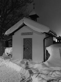 Snow covered houses by building against sky