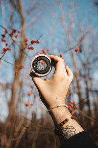 Holding a vintage camera lens towards a dingleberry bush. 