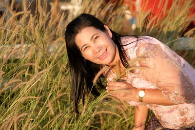 Portrait of smiling woman by plants on field