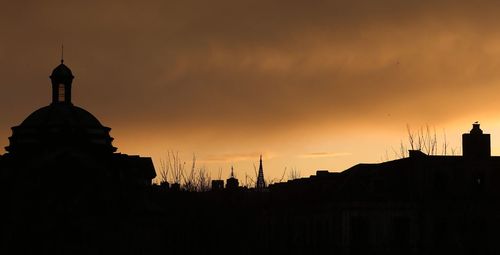 Low angle view of silhouette built structure against sky at sunset