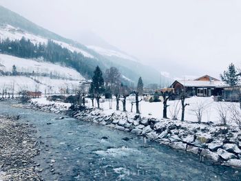 Scenic view of snow covered houses by mountains against sky