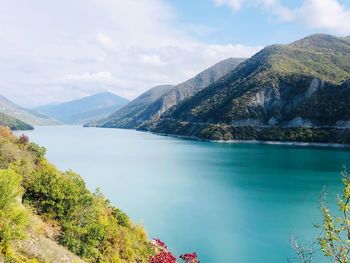 Scenic view of lake by mountains against sky