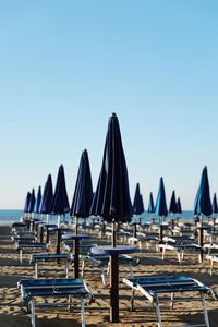 Lounge chairs on beach against clear blue sky