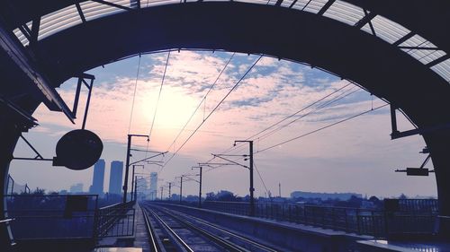 Railroad station platform against sky during sunset