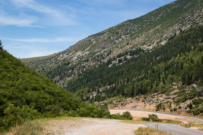 Scenic view of road by mountains against sky