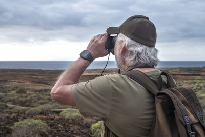 Rear view of man on shore against sky