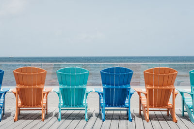 Empty chairs at beach against sky