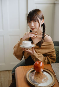 Portrait of young woman having breakfast at home
