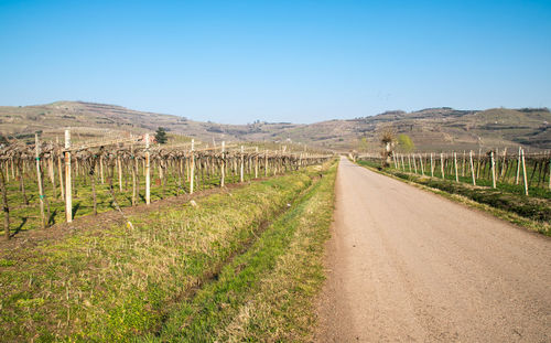 Road leading towards mountains against clear blue sky