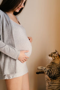 Midsection of woman holding cat standing at home