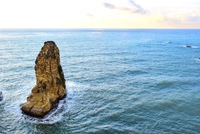 Rock formation in sea against sky