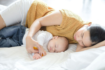 Mother and son sleeping on bed at home