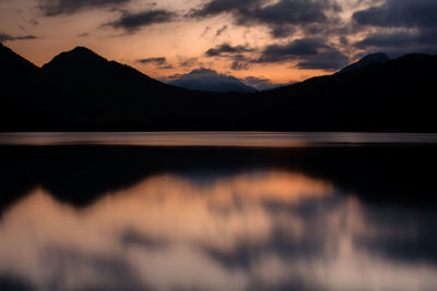 Scenic view of lake against mountains at dusk