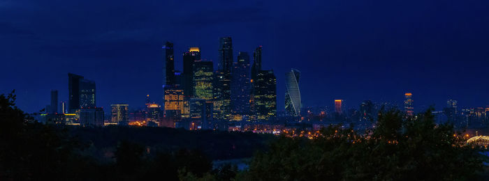 Illuminated buildings in city against sky at night