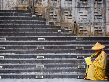 Side view of monk sitting on temple steps